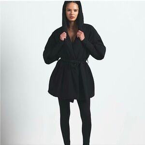 NikeSKIMS Woven Stretch Nylon Wrap Coat in the colorway Obsidian (black).